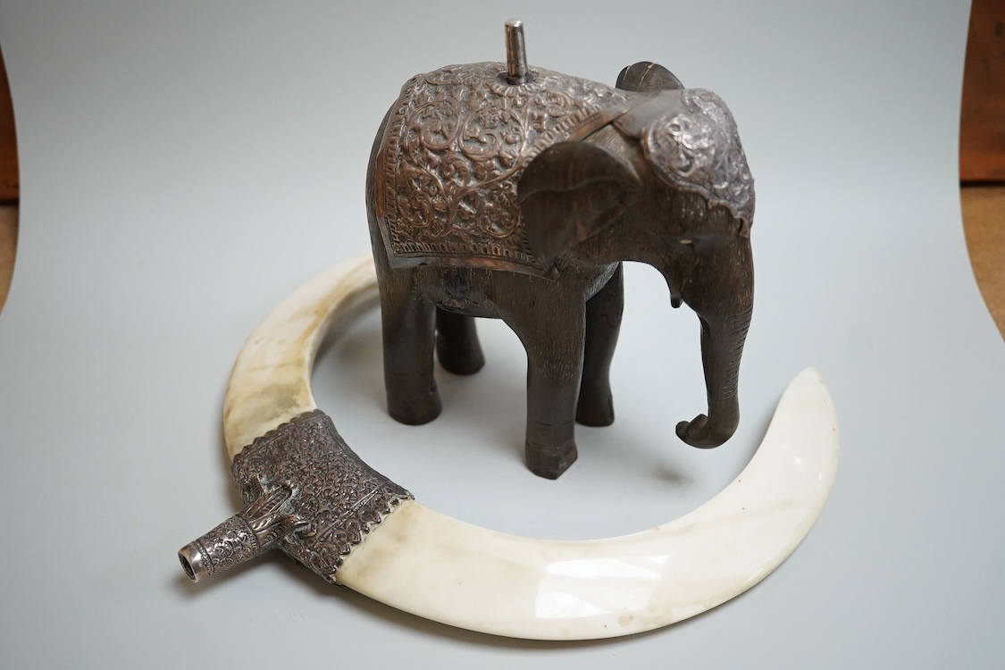 A late 19th century Indian white metal mounted carved hardwood model of an elephant, surmounted by a pair of removeable warthog tusks, overall height 40cm